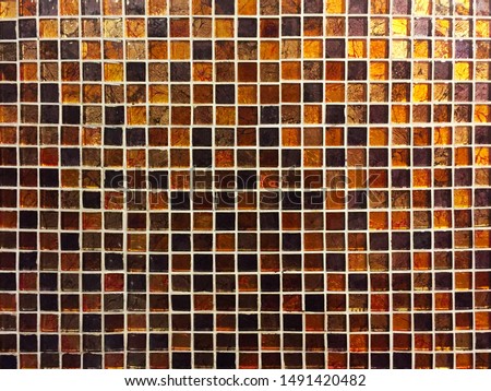 Mosaic of small square tiles in brown and amber colors. It can be used as an interesting beautiful background, texture and in the interior.