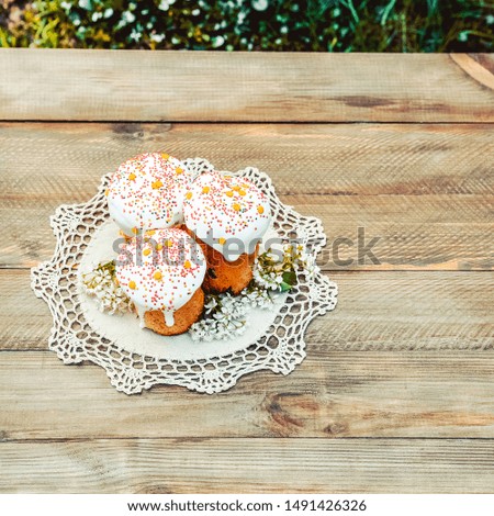 Happy Easter cake with sprinkles on white glaze. Cake on white rustic board, lace cloth, blur green plants and sun. Homemade bakery, spring holiday preparation. Selective focus, free text space.  