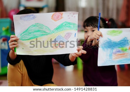 Children showing the picture or portfolio which is drawing and putting color by themselves. Education and little artist concept.                      