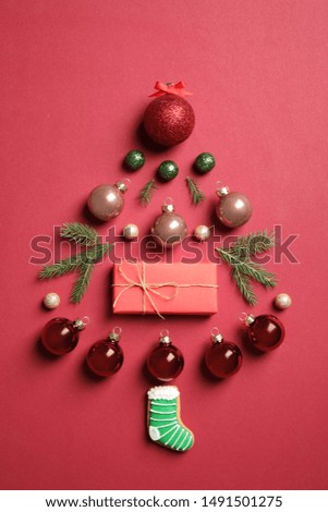 Christmas tree silhouette of fir branches and festive decoration on red background, flat lay