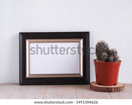  Black photo frame on white wooden with cactus.
