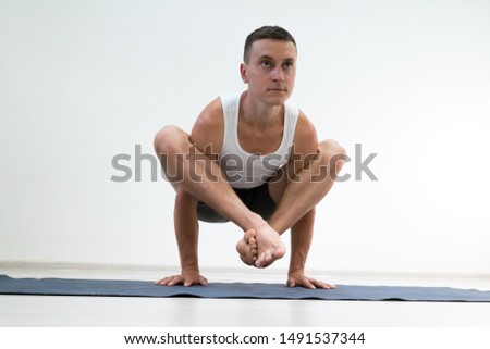 Serious young man id doing yoga poses in the studio. white background