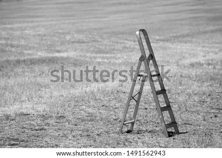 Challenge-Objective concept. Stair up with nothing around with a farm field in the background.Black and white photography.