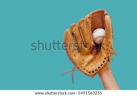 Hand in a leather baseball glove caught a ball on a green background Royalty-Free Stock Photo #1491563255