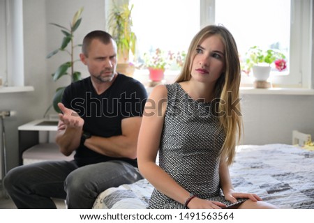 Family problems, the conflict between an adult man and a pretty girl in a room at home. They curse, sit on the bed in front of the camera, upset and displeased.
