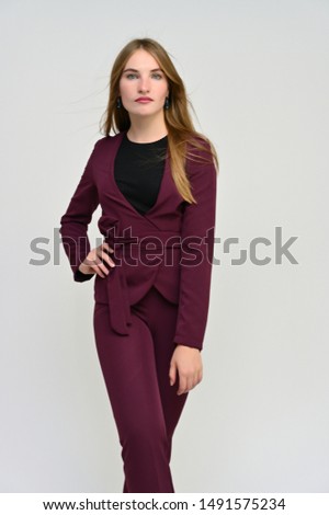 Full length vertical portrait of a pretty secretary manager brunette girl with long flowing hair in a burgundy business suit on a white background. Smiling, showing emotions.
