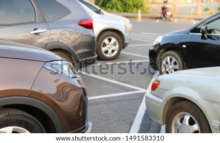 Closeup front side of brown car and other cars parking in outdoor parking lot with natural background in the evening of sunny day.