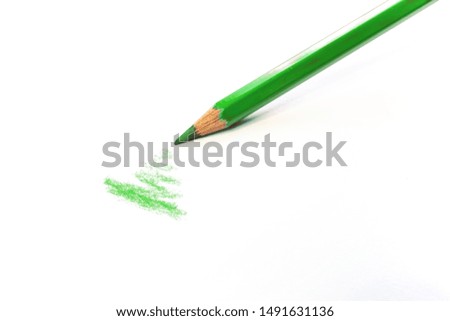 Single green pencil draws on a white surface isolated on white. Supplies for artists and schools.