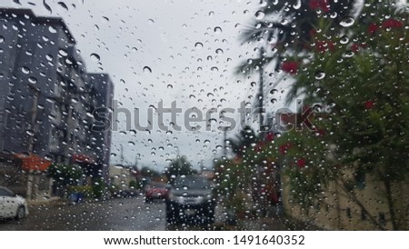 closeup rain drops on the windscreen with building and trees in frame in blur view background