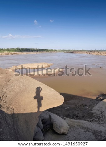 Close-up Sandstone Cliff and Shadow of a Photographer with Mekong river blurred background, Sam Phan Bok, Ubon Ratchathani, Thailand.