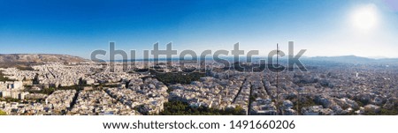Aerial panoramic view of Athens city with white buildings under blue clear skies in sunlight, Greece