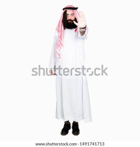 Arabian business man with long hair wearing traditional keffiyeh scarf doing stop sing with palm of the hand. Warning expression with negative and serious gesture on the face.