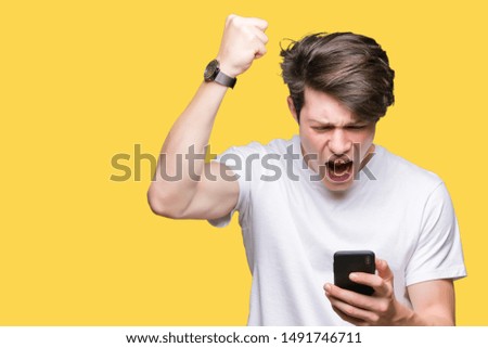 Young man using smartphone over isolated background annoyed and frustrated shouting with anger, crazy and yelling with raised hand, anger concept