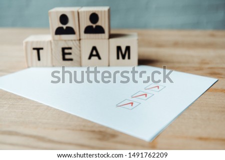 selective focus of check list near wooden cubes with team letters 