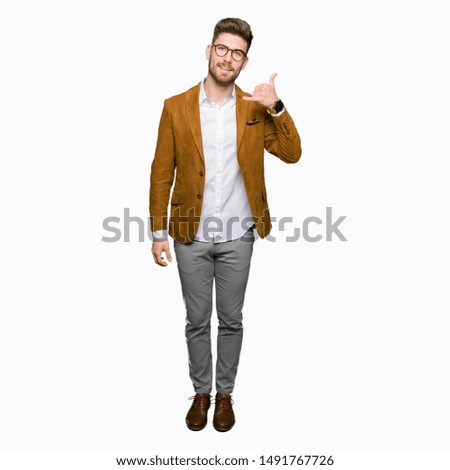 Young handsome business man wearing glasses smiling doing phone gesture with hand and fingers like talking on the telephone. Communicating concepts.