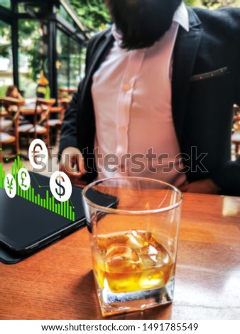 businessman on the cafe restaurant bar with his pro tablet drinking whiskey and work remotely economy currency holograms on the screen