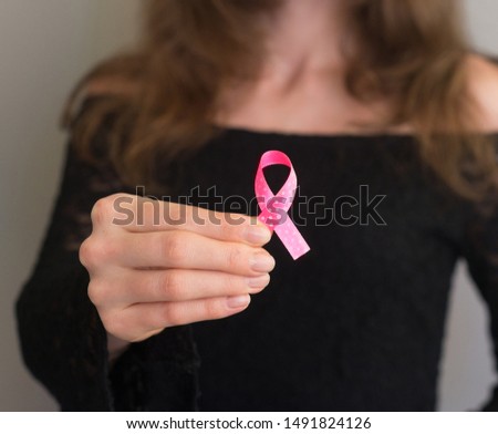 The girl holding a pink ribbon, symbol of cancer. Breast cancer awareness month.