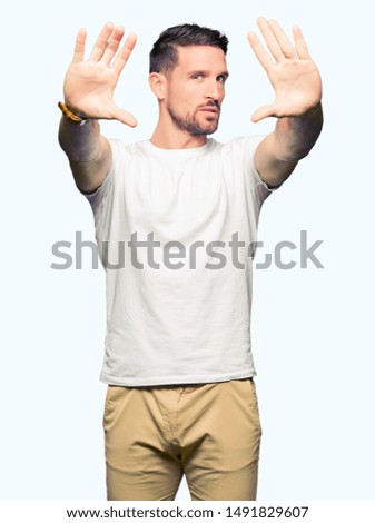 Handsome man wearing casual white t-shirt Smiling doing frame using hands palms and fingers, camera perspective