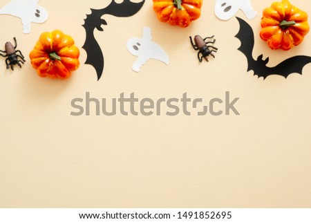 Halloween composition. Halloween decorations, pumpkins, paper ghost, spiders on pastel beige background. Halloween concept. Flat lay, top view, copy space