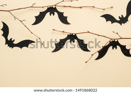 Halloween paper decorations on pastel beige background. Black bats sitting on branch. Halloween concept. Flat lay, top view, copy space