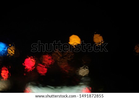 The lights are blurry in many colors when it rains at night. There is a watermark on the windshield.