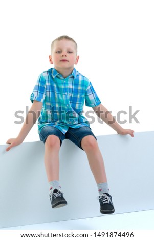 A little boy is looking from behind an empty banner.