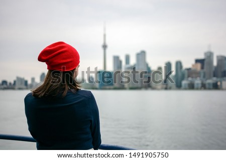 Woman traveler enjoying the view of Toronto city skyline with iconic landmarks and skyscrapers. Ferry ride to Centre Island. Rear view