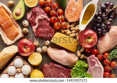 Top view of assorted meat, poultry, fish, eggs, fruits, vegetables, cheese, olive oil and baguette Royalty-Free Stock Photo #1491907571