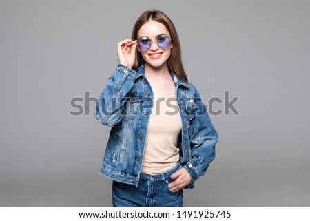 Smiling happy woman making selfie photo isolated on white studio background dressed jeans and denim shirt wearing yellow sunglasses hipster style outfit