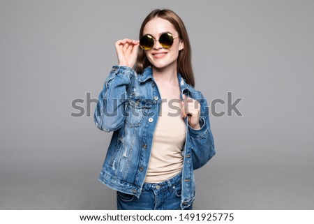 Young pretty woman with sunglasses wear in jeans jacket on gray background