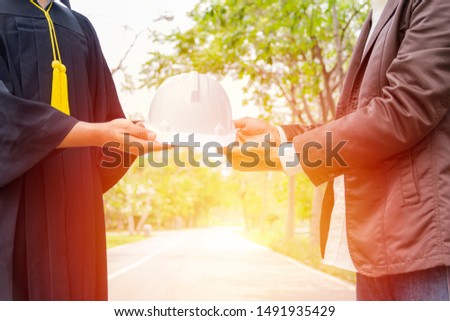 A picture of a graduate receiving a helmet from an engineer It represents the career of graduates in the future.He is an engineer Royalty-Free Stock Photo #1491935429