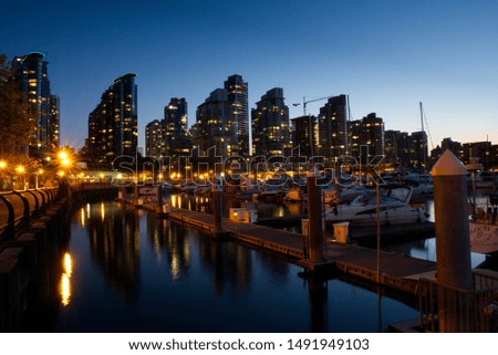 A picture of Vancouver with a small harbor in the foreground