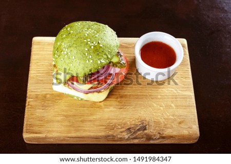 Green burger with cutlet and vegetables on a cutting wooden board. place for text
