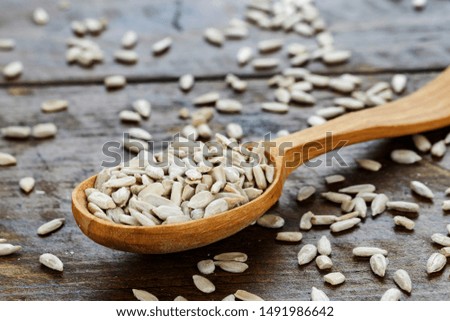 peeled sunflower seeds in a wooden spoon on a wooden background. place for text
