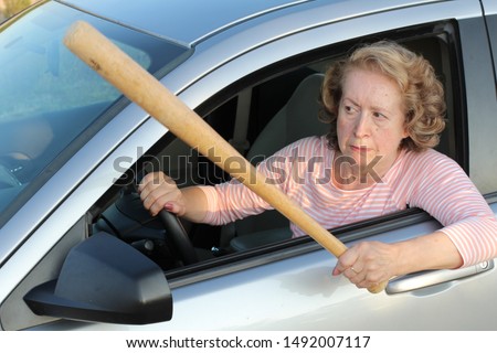 Angry mature female driver holding baseball bat  Royalty-Free Stock Photo #1492007117