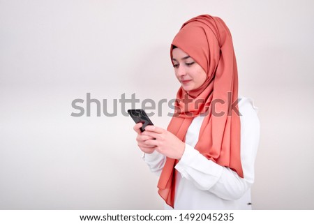 Muslim woman typing message and looking her mobile phone screen, muslim girl write message
