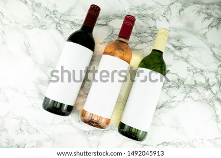 Three bottles of wine with blank labels on marble table
