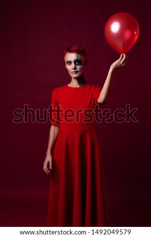 Sad scary woman in red with red hair and red balloon on red background