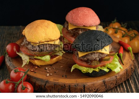 Mini burgers in red, yellow and black colors on a wooden Board.