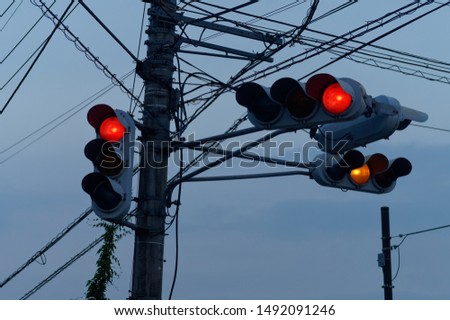 Silhouette of four traffic lights hanging from the same post and electricity cables at dusk in Japan.