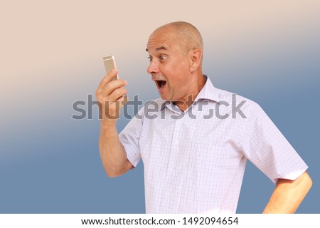funny man in a light shirt with a silly look looks, opening his mouth to his smartphone, technology concept, horizontal, close-up, copy space