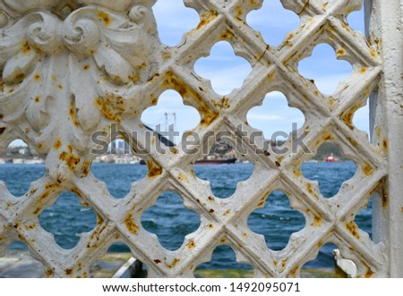 Detail of a vintage forged metal gate looking on the European and Asian shores of the Bosphorus strait in Istanbul, Turkey, with a partial view of boats and the Bosphorus Bridge.