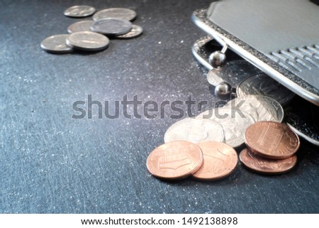 Close-up metal money on a dark surface is scattered from a gray old wallet . Shallow depth of field. Coins, American cents. Cash payment concept. Saving budget