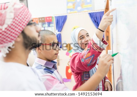 Gulf Arab teacher with students on whiteboard 