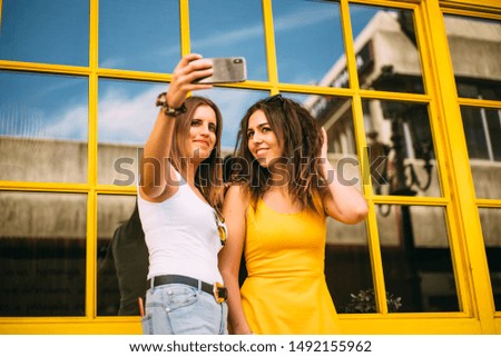 Two women friends take a picture with mobile phone