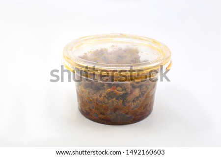 Chili paste in plastic jar on white background.