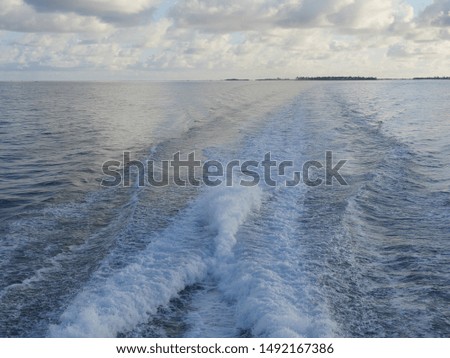 Wide shot of the ocean with rippling waters created by a boat engine 