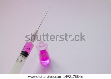 ampoule with pink injection and pink syringe on a purple background