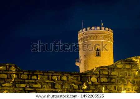 Medieval ruin of a watch tower at night with stone wall in the foreground