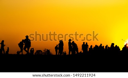 Silhouette of many tourists are taking pictures by smart phone on the top of the mountain during sunset times.